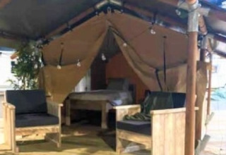 Interieur van de Lodge ‘Insolite Bivak’ safaritent bij Flower Camping la Pinède met stoelen en bed.