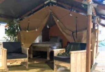 Interieur van de Lodge ‘Insolite Bivak’ safaritent bij Flower Camping la Pinède met stoelen en bed.
