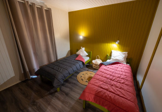 Kamer in Chalet «l'O douce» met twee eenpersoonsbedden, kleurrijke dekbedden en warme verlichting, Flower Camping la Pinède.