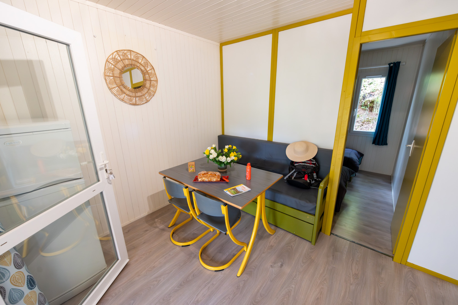 Eethoek met bank, tafel, stoelen en spiegel in Chalet 'Comfort Authentiek' bij Flower Camping la Pinède, Frankrijk.