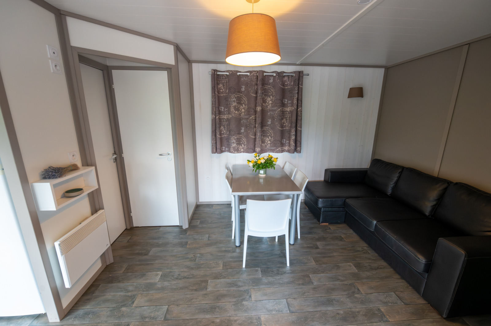 Interieur van Chalet «Confort Vercors» bij Flower Camping la Pinède met bank en eettafel.