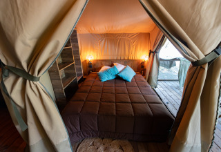 Knusse slaapkamer met tweepersoonsbed in de safaritent Lodge Insolite Pinède op Flower Camping la Pinède.