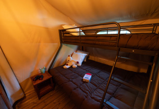 Binnenzicht van safaritent Lodge Insolite Pinède op Flower Camping la Pinède met stapelbedden en speelgoed.