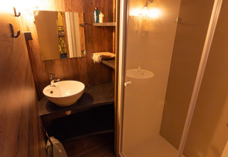 Badkamer met houten wanden, douchecabine, wastafel en spiegel in Lodge Insolite Pinède bij Flower Camping la Pinède, Frankrijk.