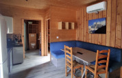 Interior of chalet with wooden walls, blue seating area, kitchen, and table, accessible for limited mobility.