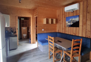 Interior of chalet with wooden walls, blue seating area, kitchen, and table, accessible for limited mobility.