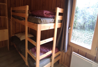 A cozy wooden room with bunk beds at the mobility-friendly Chalet at Family's Camping Le Savoy in France.
