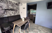 Alloggio glamping moderno con area lounge elegante, tavolo da pranzo e angolo cottura visibili.