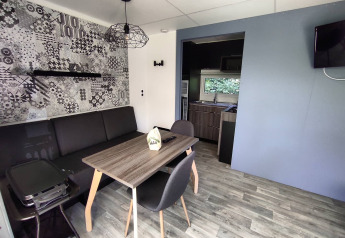 Hébergement glamping moderne avec salon élégant, table à manger et kitchenette en arrière-plan.
