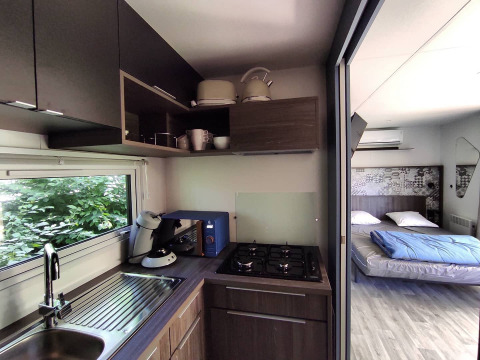 Angolo cottura moderno e camera da letto in una tiny house al Family's Camping Le Savoy, Francia, arredamento elegante.