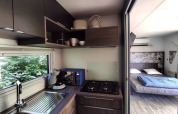 Kompakte Küche und Schlafzimmer in einem Tiny House im Family's Camping Le Savoy, Frankreich, mit moderner Ausstattung.