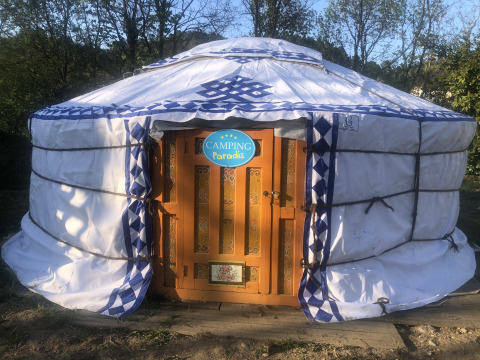 Foto van een traditionele yurt-tent bij Camping Paradis met houten deur en omringd door bomen.