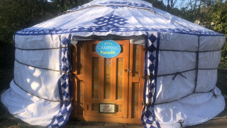 Foto van een traditionele yurt-tent bij Camping Paradis met houten deur en omringd door bomen.