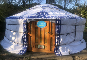 Foto van een traditionele yurt-tent bij Camping Paradis met houten deur en omringd door bomen.