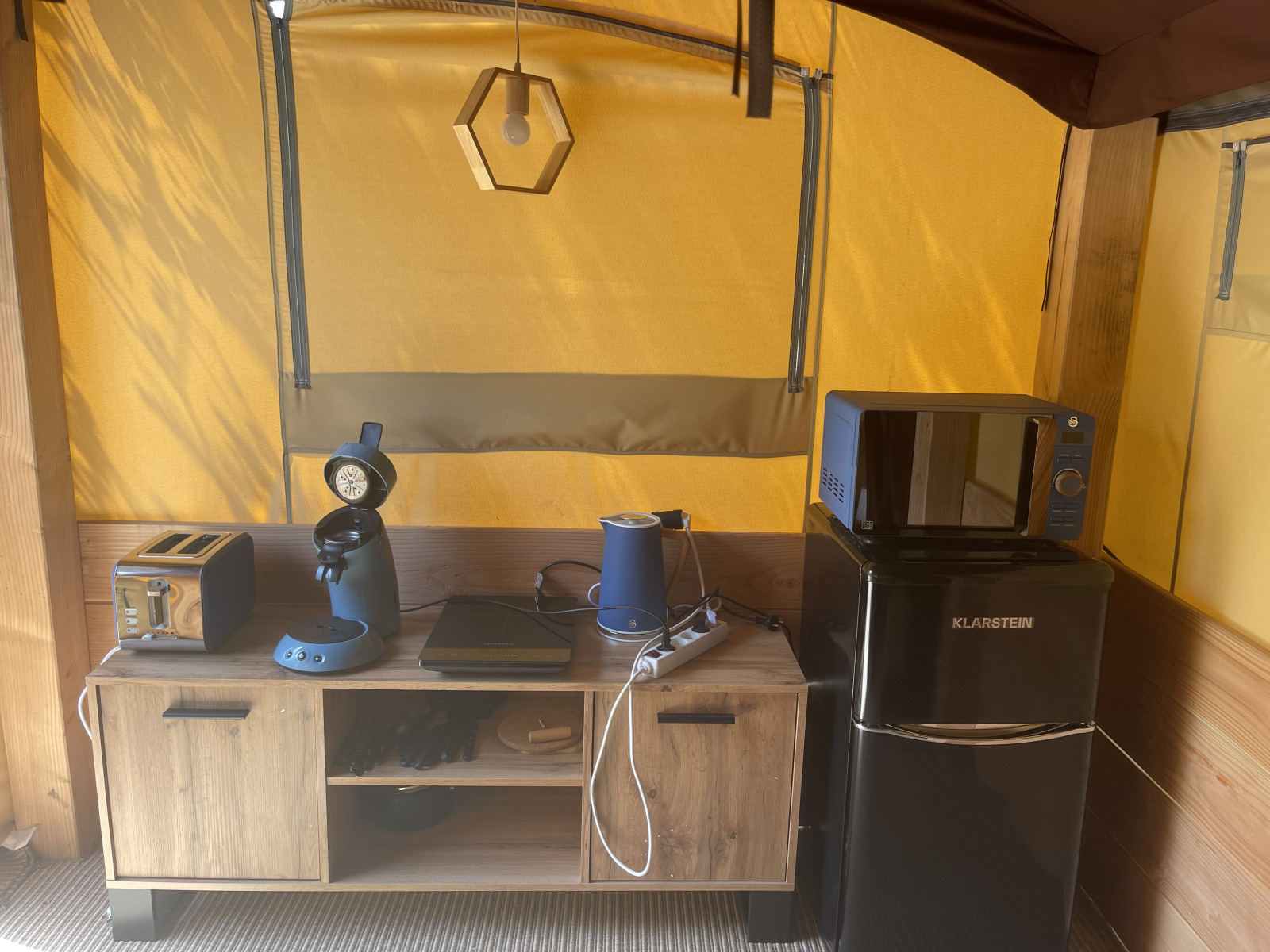 Keukenhoek in de Avonturiers tent met broodrooster, koffiezetapparaat, waterkoker en koelkast op Camping Paradis Family des Issoux, Frankrijk.