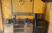 Rincón de cocina en la tienda Avonturiers con tostadora, cafetera, hervidor y nevera en Camping Paradis Family des Issoux, Francia.
