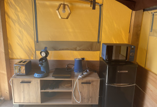 Keukenhoek in de Avonturiers tent met broodrooster, koffiezetapparaat, waterkoker en koelkast op Camping Paradis Family des Issoux, Frankrijk.