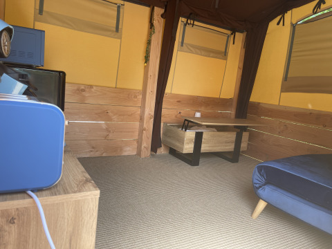 Binnenkant van de Avonturiers tent op Camping Paradis Family des Issoux in Frankrijk, met houten meubels.