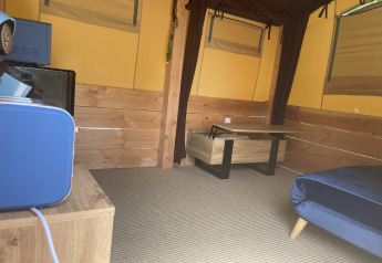 Interno della tenda Avonturiers al Camping Paradis Family des Issoux in Francia, con arredi in legno e blu.