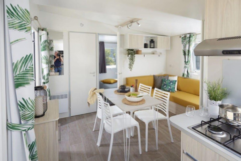 Licht interieur van Comfort Mobile Home op Camping Paradis Family des Issoux met eettafel en zitbank.