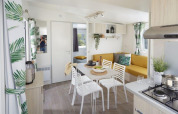 Intérieur lumineux du Comfort Mobile Home au Camping Paradis Family des Issoux, table à manger et canapé.