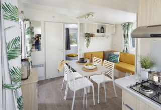 Licht interieur van Comfort Mobile Home op Camping Paradis Family des Issoux met eettafel en zitbank.