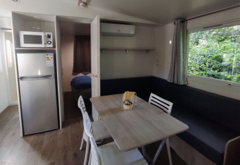 Woonkamer in Stacaravan CONFORT 30m² op Family's Camping Le Savoy met eettafel en keukenhoek.