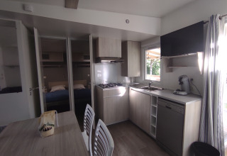 Cuisine et coin repas du Stacaravan CONFORT 30m² au Family's Camping Le Savoy avec vue sur la chambre.