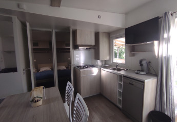 Cuisine et coin repas du Stacaravan CONFORT 30m² au Family's Camping Le Savoy avec vue sur la chambre.
