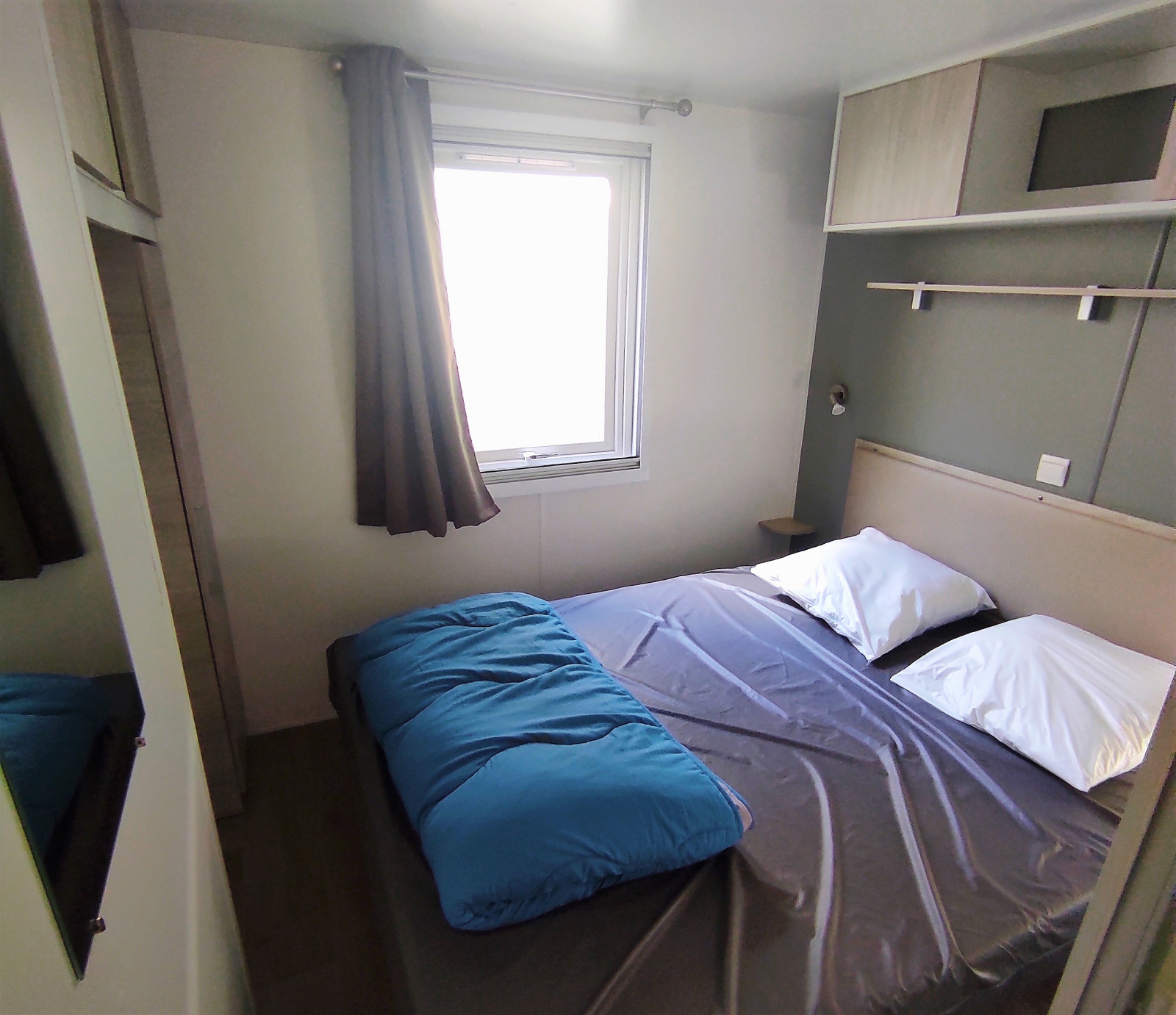 Moderne slaapkamer in Stacaravan CONFORT 30m², Family's Camping Le Savoy, Frankrijk, met tweepersoonsbed en raam.