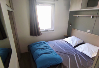 A modern bedroom at Stacaravan CONFORT 30m², Family's Camping Le Savoy, France, with a double bed and window.