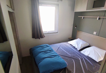 Dormitorio moderno en Stacaravan CONFORT 30m² de Family's Camping Le Savoy, Francia, con cama doble y ventana.