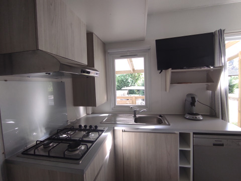 Cocina moderna en Stacaravan CONFORT 30m² de Family's Camping Le Savoy, Francia, con estufa y ventana.