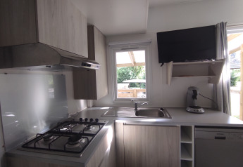 Cocina moderna en Stacaravan CONFORT 30m² de Family's Camping Le Savoy, Francia, con estufa y ventana.