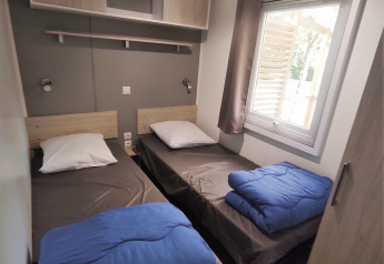 Twee enkele bedden in een lichte kamer van Stacaravan CONFORT 30m², Family's Camping Le Savoy, Frankrijk.
