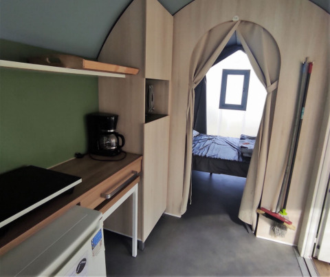 Indvendig udsigt af Coco Sweet safaritelt, der viser tekøkken og soveværelse på Family's Camping Le Savoy.