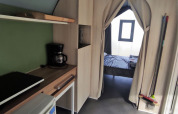 Interior view of a Coco Sweet safari tent showing a kitchenette and bedroom at Family’s Camping Le Savoy, France.