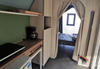 Indvendig udsigt af Coco Sweet safaritelt, der viser tekøkken og soveværelse på Family's Camping Le Savoy.