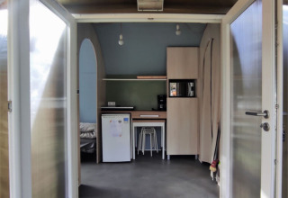 Indgang til et Coco Sweet safari-telt på Family's Camping Le Savoy i Frankrig med åbne døre og køkken.