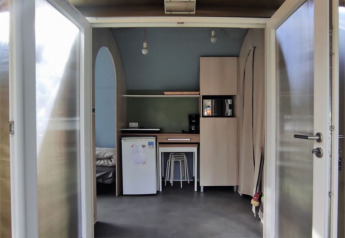Entrada a una tienda safari Coco Sweet en Family's Camping Le Savoy, Francia, con puertas abiertas y cocina.