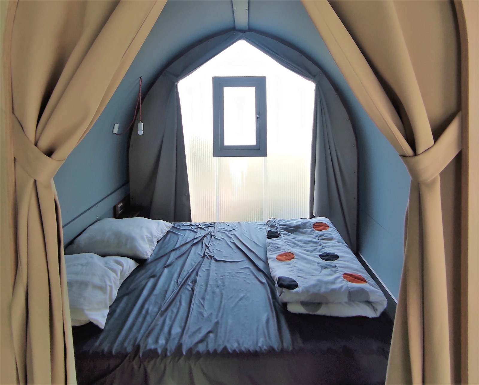 Interieur van een Coco Sweet safaritent met tweepersoonsbed en raam bij Family's Camping Le Savoy.