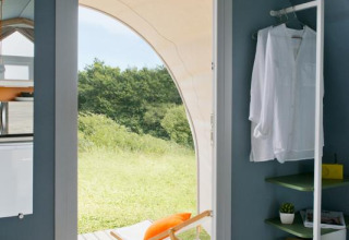Interno della tenda Coco Sweet con porta aperta, sdraio sulla terrazza e vista verde a Provence Vallée, Francia.