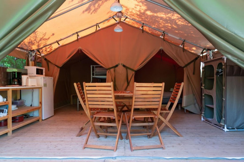 Innenansicht eines komfortablen Freeflower-Safari-Zeltes mit Holzmöbeln auf Flower Camping Provence Vallée.