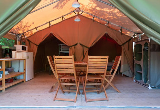 Innenansicht eines komfortablen Freeflower-Safari-Zeltes mit Holzmöbeln auf Flower Camping Provence Vallée.