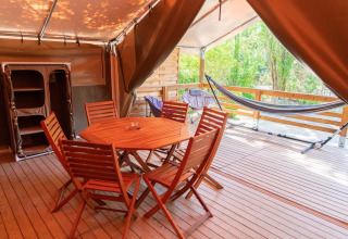 Holzterrasse mit Esstisch, Stühlen und Hängematte im Safari-Zelt bei Flower Camping Provence Vallée in Frankreich.