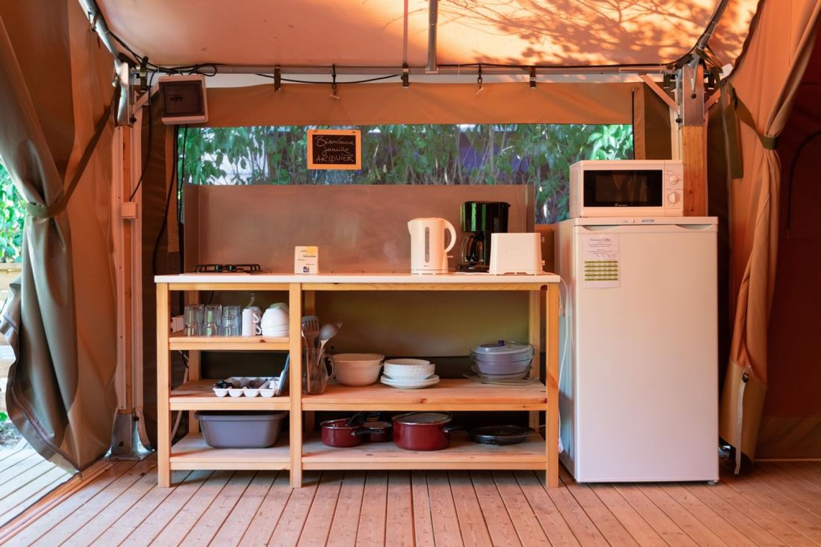 Keukenopstelling in safaritent met houten rekken, koelkast en magnetron bij Flower Camping Provence Vallée.