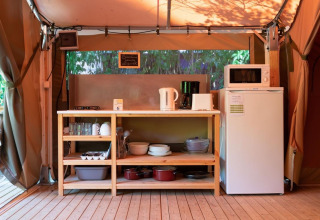 Küchenbereich im Safarizelt mit Holzregal, Kühlschrank und Mikrowelle, Flower Camping Provence Vallée.