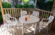 Terrasse mit vier weißen Kunststoffstühlen und rundem Tisch im Mobile Home «ECO Lodgia» in Provence Vallée.