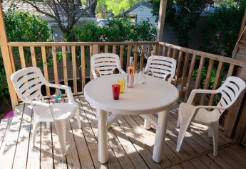 Udendørs terrasse med fire hvide plastikstole og et rundt bord på Mobile Home «ECO Lodgia» i Provence Vallée.