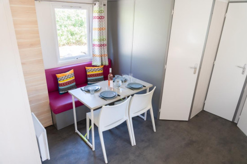 Spiseområde i Mobile Home «ECO Lodgia» ved Flower Camping Provence Vallée, med bord, stole og farverige puder.